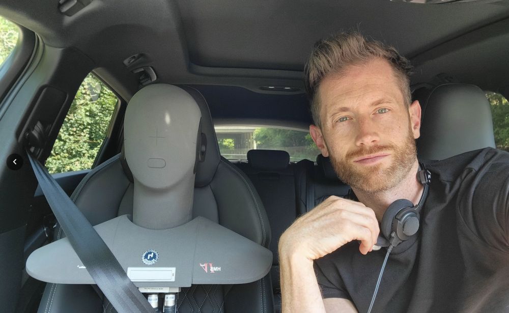 Jonathan Benson en un coche de pruebas con una cabeza acústica de medición en el asiento del acompañante