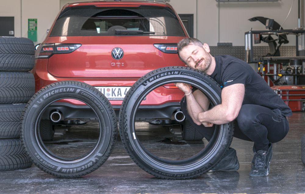 Jonathan Benson con dos neumáticos Michelin delante de un Volkswagen Golf GTI de pruebas