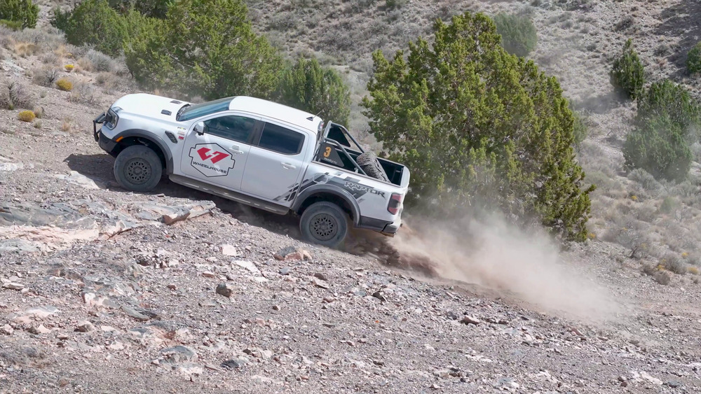 Ford Ranger Raptor blanco subiendo una pendiente rocosa en Five Mile Pass, con polvo detrás de las ruedas traseras
